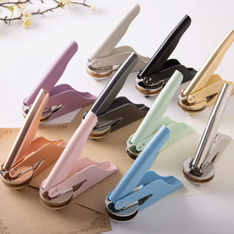 Book embossers shown in a range of finishes including gold, silver, black, green, blue, pink, and rose gold